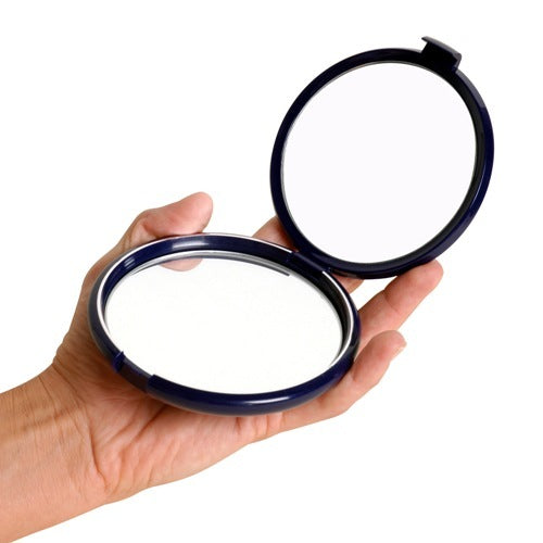 Image of hand holding open, round compact magnifying mirror against white background.