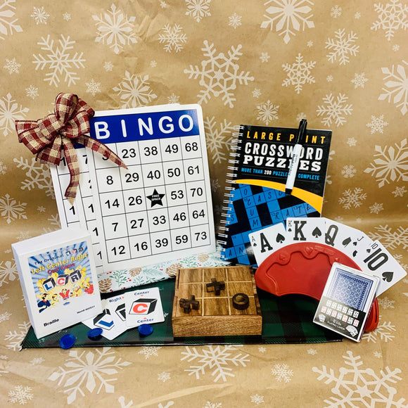 The Fundle- 3 large print bingo cards, large print crossword puzzle book, bold writer 20, lcr game, tic tac toe, card holder and large print playing cards shown against a snowflake background