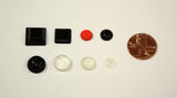 8 individual bump dots of assorted colors, shapes and sizes shown next to a penny on a white background.  The largest is about the size of a penny. 